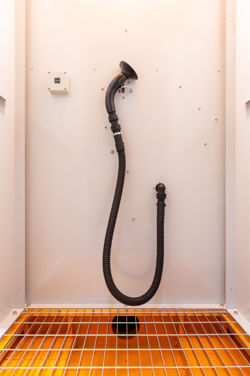 Interior shot of the JetBlack Safety standard Personnel Cleaning Booth showing the air blower hose and bottom grill with extraction outlet